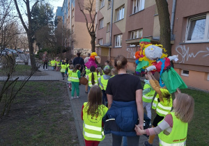 Przedszkolaki na spacerze alejkami osiedla z marzannami.