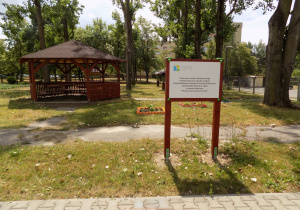 Na zdjęciu widać wyposażenie ogrodu: altanę i tablicę informacyjną o dofinansowaniu śnieżki dydaktycznej.