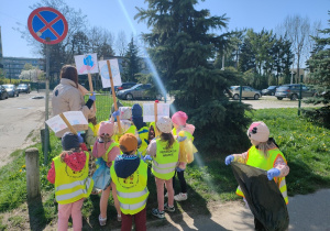 Dzieci w kamizelkach stoją przed przedszkolem.