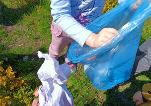 Dziecko wrzuca papier do niebieskiego worka.