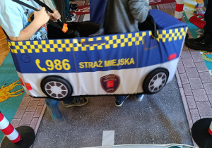 Dzieci w strojach pojazdów poruszają się po drodze.