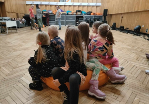 Dzieci siedzą na pufie w studio nagrań.