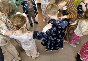 Dzieci stoją w kole i trzymają za ramiona kolegów i koleżanek.