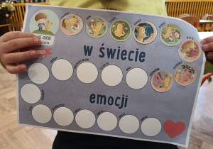 Dziecko pokazuje wypełnioną kartę emocji.