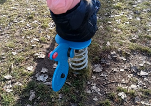 Dziewczynka buja się na koniku na przedszkolnym placu zabaw.