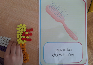 Dziecko układa z Darów Froebla szczotkę do włosów.
