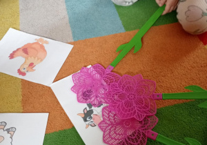 Dzieci uderzają klapkami na muchy w ilustrację przedstawiającą krowę.