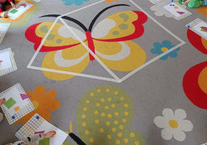 Dzieci smarują klejem i przyklejają kolejne elementy domu na kartki.