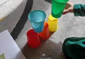 Dziecko układa plastikowy kubek według instrukcji obrazkowej.
