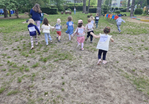 Dzieci z grupy czerwonej razem z nauczycielką biorą udział w biegu.