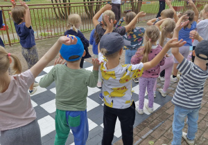 Starszaki na tarasie z uniesionymi do góry rękoma.