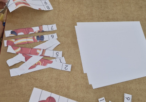 Dzieci wycinają po linii puzzle przedstawiające postać strażaka.