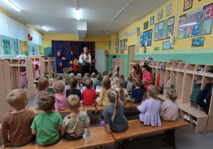 Dzieci z młodszych grup siedzą na ławeczkach podczas audycji z Bachmanem.