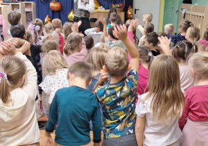 Dzieci podczas audycji muzycznej podnoszą ręce do góry.