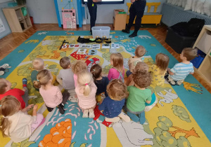Dzieci z grupy zielonej siedzą na dywanie.