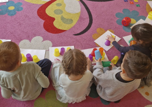 Dzieci układają wieżę z kolorowych kubeczków według wzoru.