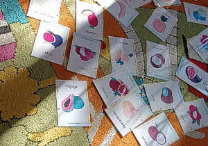 Na dywanie leżą obrazki owoców.