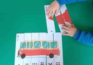 Dzieci układają puzzle, na których są różne pojazdy.