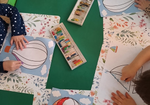 Dzieci kolorują pastelami obrazki balonów i żaglówek.