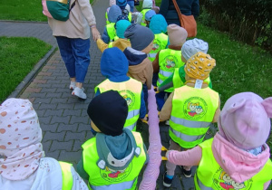 Dzieci idą parami, trzymając się pluszowego węża.