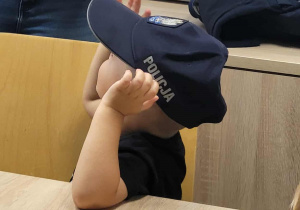 Chłopiec przymierza czapkę policyjną.