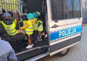 Dzieci stoją w wozie policyjnym.