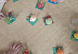 Dzieci przy stoliku bawią się wykonanymi przez siebie jeżami.