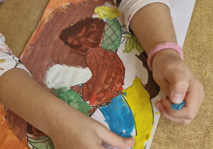 Dziewczynka z wykorzystaniem plasteliny wylepia część parasola.