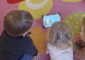 Dzieci na tablecie oglądają film związany z segregacją śmieci.