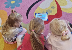 Dziewczynki na tablecie oglądają film związany z segregacją śmieci.