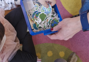 Dziecko wybiera z pojemnika naklejkę.