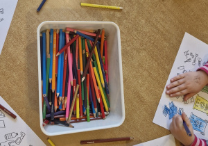 Dzieci kolorują kolorowankę - kosze na śmieci oraz różne odpady.