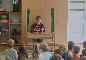 Dzieci oglądają przedstawienie "Trzy świnki" prezentowane przez nauczyciela.