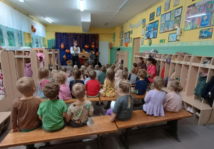 Dzieci siedzą  na ławkach i słuchają audycji muzycznej z serii "Spotkania z Bachmanem".