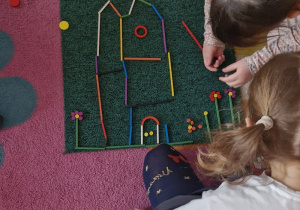 Dziewczynki układają wspólnie zamek z darów zabawy Froebla.