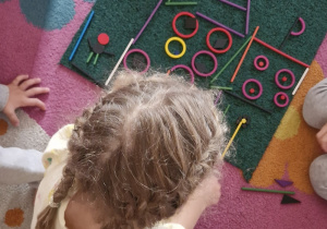 Dziewczynka dokłada do pracy grupowej elementy z darów zabawy Froebla tworzące zamek.