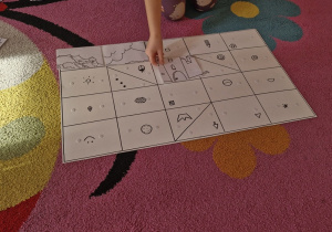 Dziecko układa na planszy kolejny element zakodowanych puzzli.