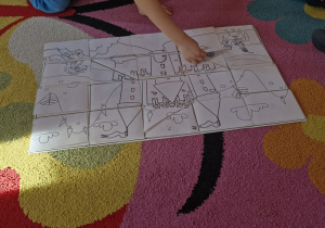 Dziecko układa na planszy ostatni element zakodowanych puzzli.
