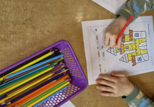 Dzieci przy stoliku kolorują zamek według podanego kodu.