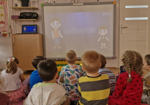 Dzieci oglądają film na tablicy multimedialnej.