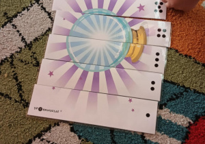 Dziecko układa pociętą na kawałki magiczną kulę.