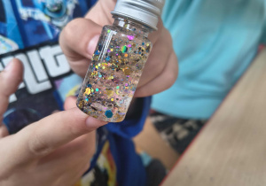 Dziecko w ręce trzyma wykonany przez siebie magiczny eliksir.