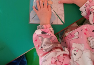 Dziewczynka układa pociętą na kawałki ilustrację przedstawiającą prawa dziecka.