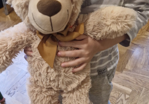 Dziecko trzyma w rączkach swojego misia.