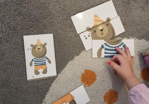 Dziewczynka układa według wzoru pociętego na kawałki misia.