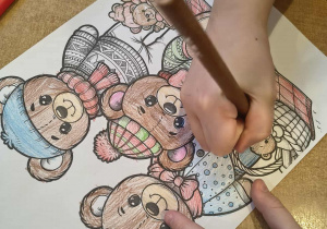 Dziecko przy stoliku koloruje misie.