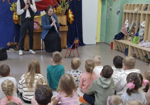 Dzieci obserwują jak kobieta gra na oboju.