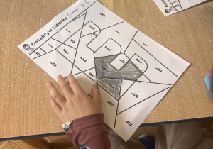 Dziecko wyszukuje i koloruje literę E wśród innych liter.