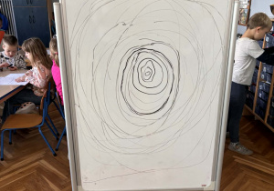 Litera "O" kreslona przez dzieci na tablicy suchościeralnej.