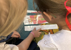 Dzieci układają pociętą na kawałki ilustrację przedstawiającą herb Warszawy.